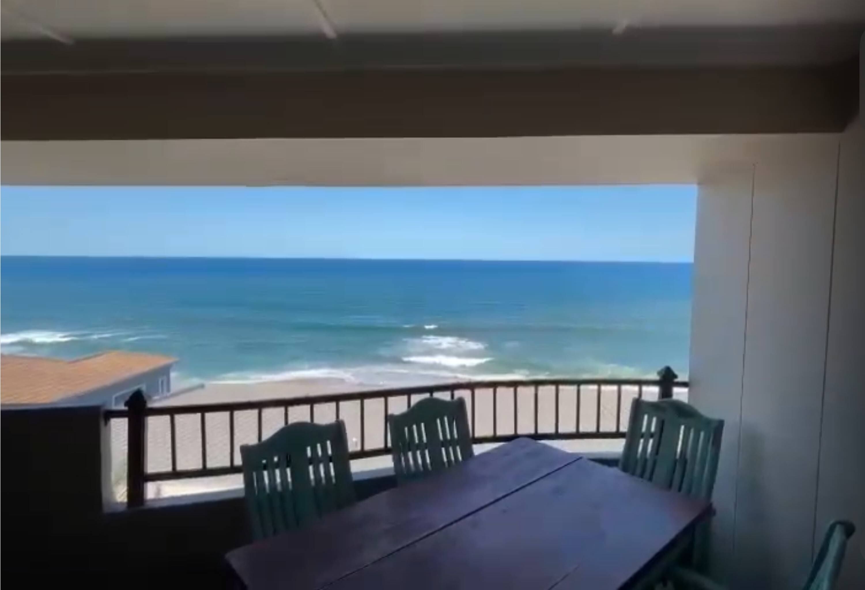 A balcony with a table and chairs overlooking the ocean.