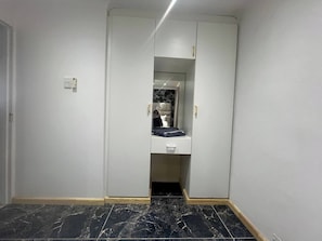 A narrow hallway with a mirrored closet door, a small white cabinet, and a black tiled floor. - Luxurious Beach Apartment (Westbrook)