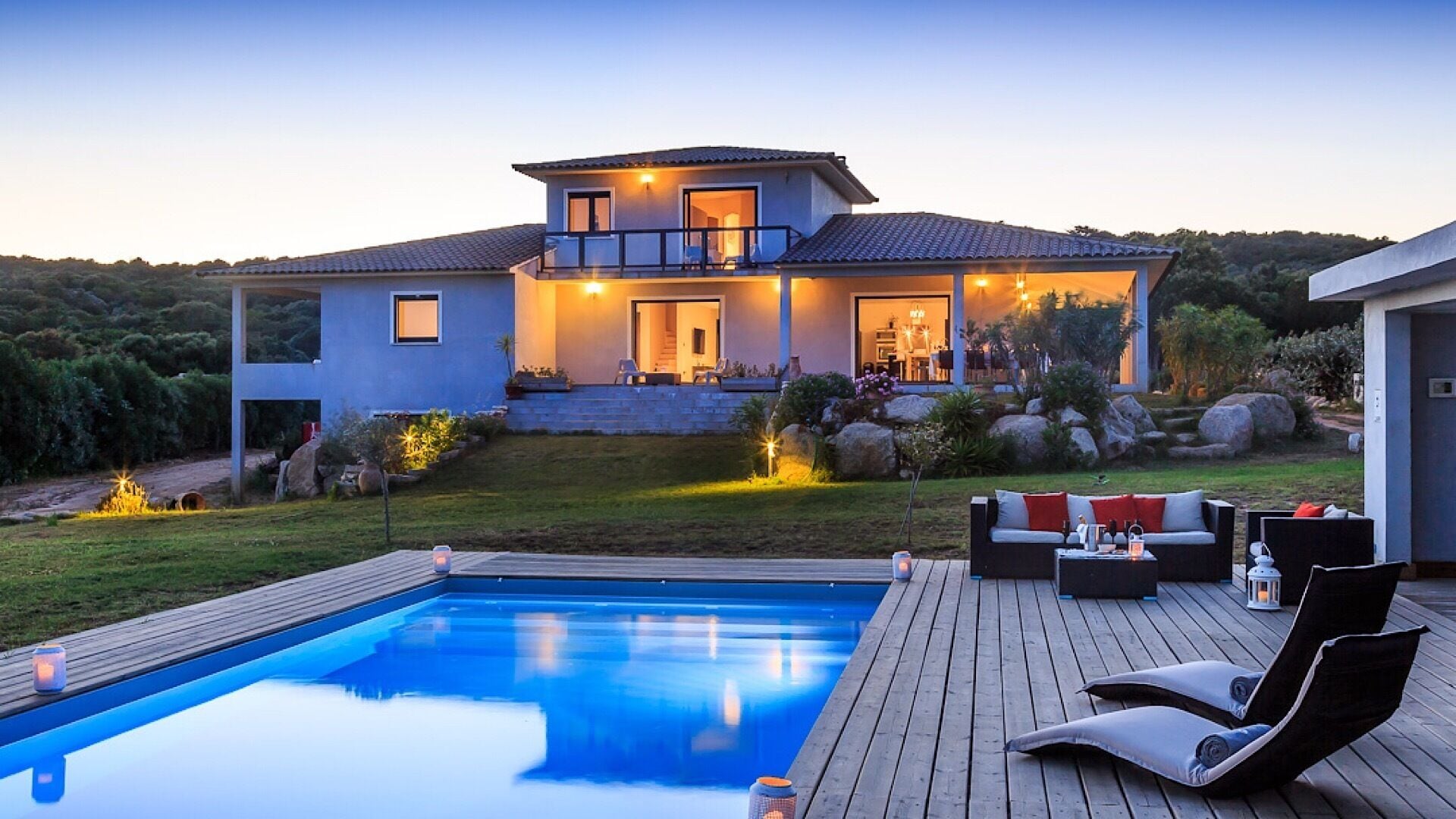 Une maison moderne dotée d’une piscine, d’un espace salon extérieur et d’un jardin bien entretenu.
