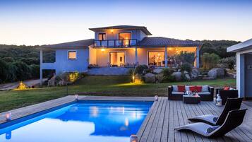 A modern house with a swimming pool, outdoor seating, and a well-maintained garden.