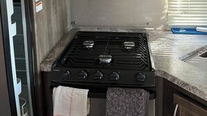 A compact kitchen with a microwave, oven, and gas stove.