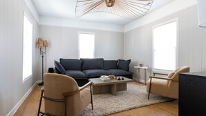 A modern living room with a sofa, two armchairs, a coffee table, and a floor lamp. - The Coziest Home Base in the Twin Cities (Crystal City)