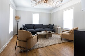 Uma sala de estar moderna com sofá, duas poltronas, uma mesa de centro e um abajur.