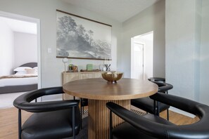 Uma área de refeições moderna com uma mesa redonda de madeira, cadeiras pretas e uma tigela decorativa.