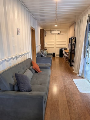Un espacio habitable pequeño con sofá, una mesita y una estantería.