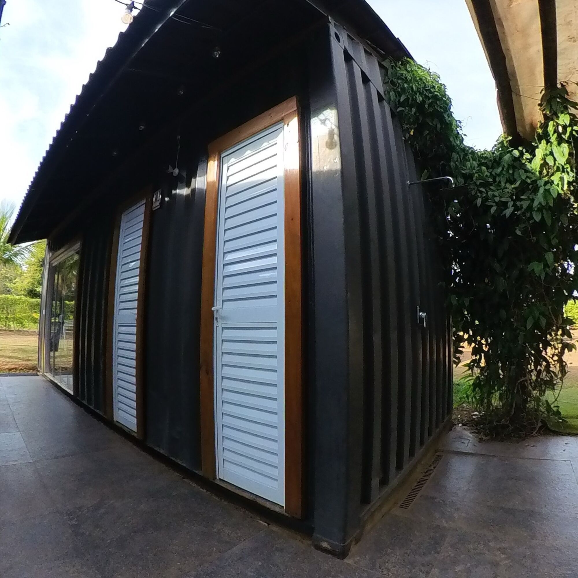 Um edifício com fachada preta, duas portas brancas e uma pequena janela.