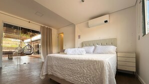 Ein Schlafzimmer mit einem Bett, einem Nachttisch, einem Fenster und Blick auf einen Außenbereich.
