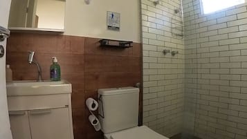 Un baño con inodoro, lavamanos y zona de ducha.
