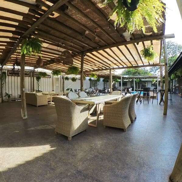 An outdoor patio area with wicker furniture, a pool, and hanging plants.
