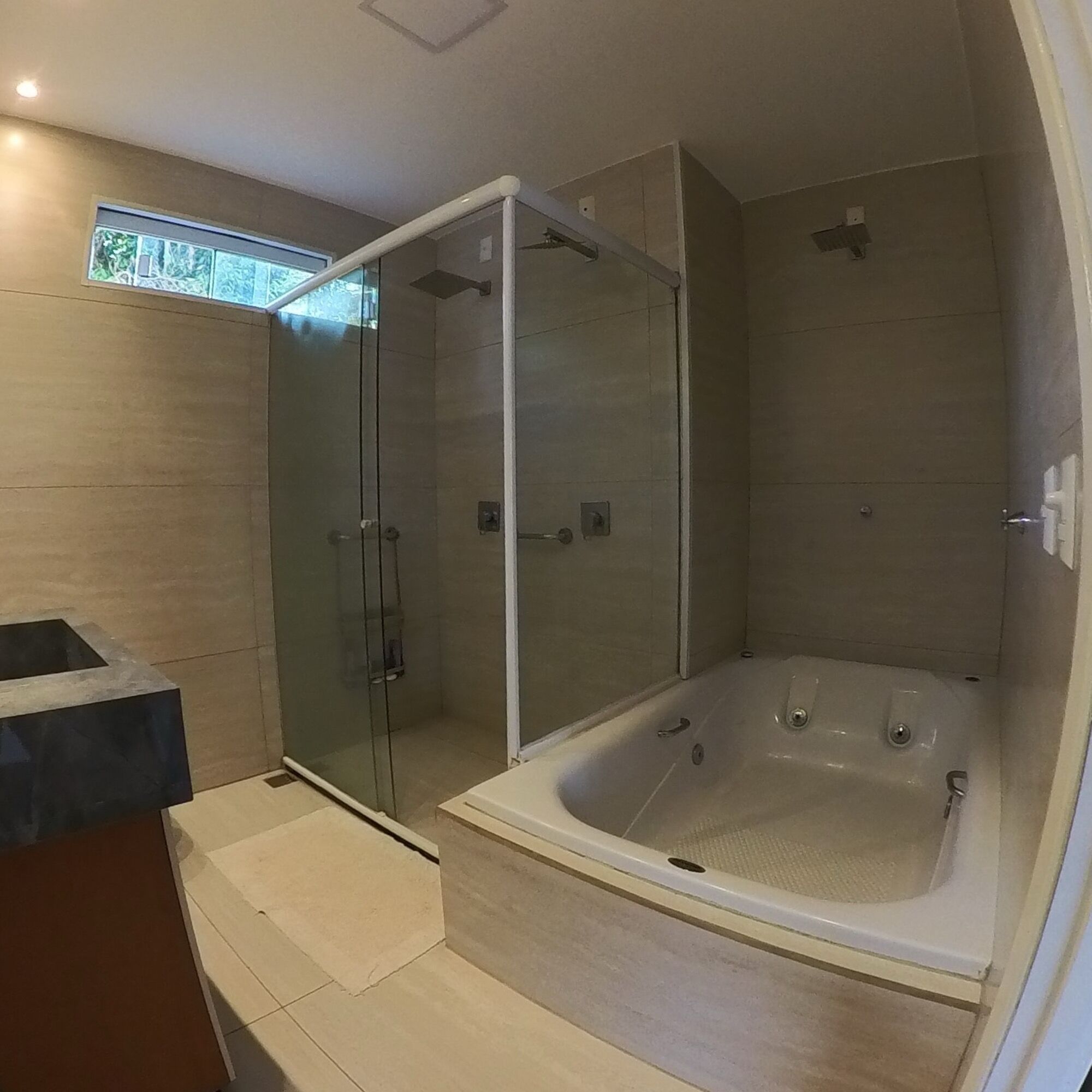 Ein modernes Badezimmer mit einer Glaskabine zur Dusche, einer freistehenden Badewanne und einem Waschtisch.