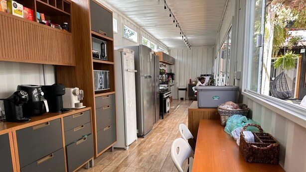 Una cocina moderna con electrodomésticos integrados, un comedor con mesa de madera y vistas al exterior.