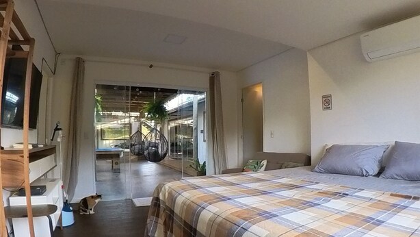Ein Hotelzimmer mit einem Bett, einem Schreibtisch und einem Stuhl. Es gibt ein Fenster mit Vorhängen und Blick nach draußen.
