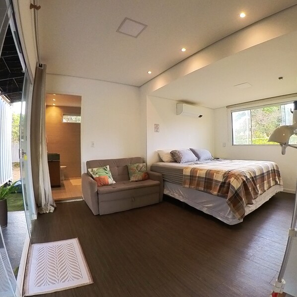 A bedroom with a bed, a sofa, and a window.