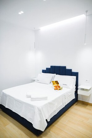 Ein Hotelzimmer mit einem Bett, weißen Laken, einem Nachttisch und einer Nachttischlampe.