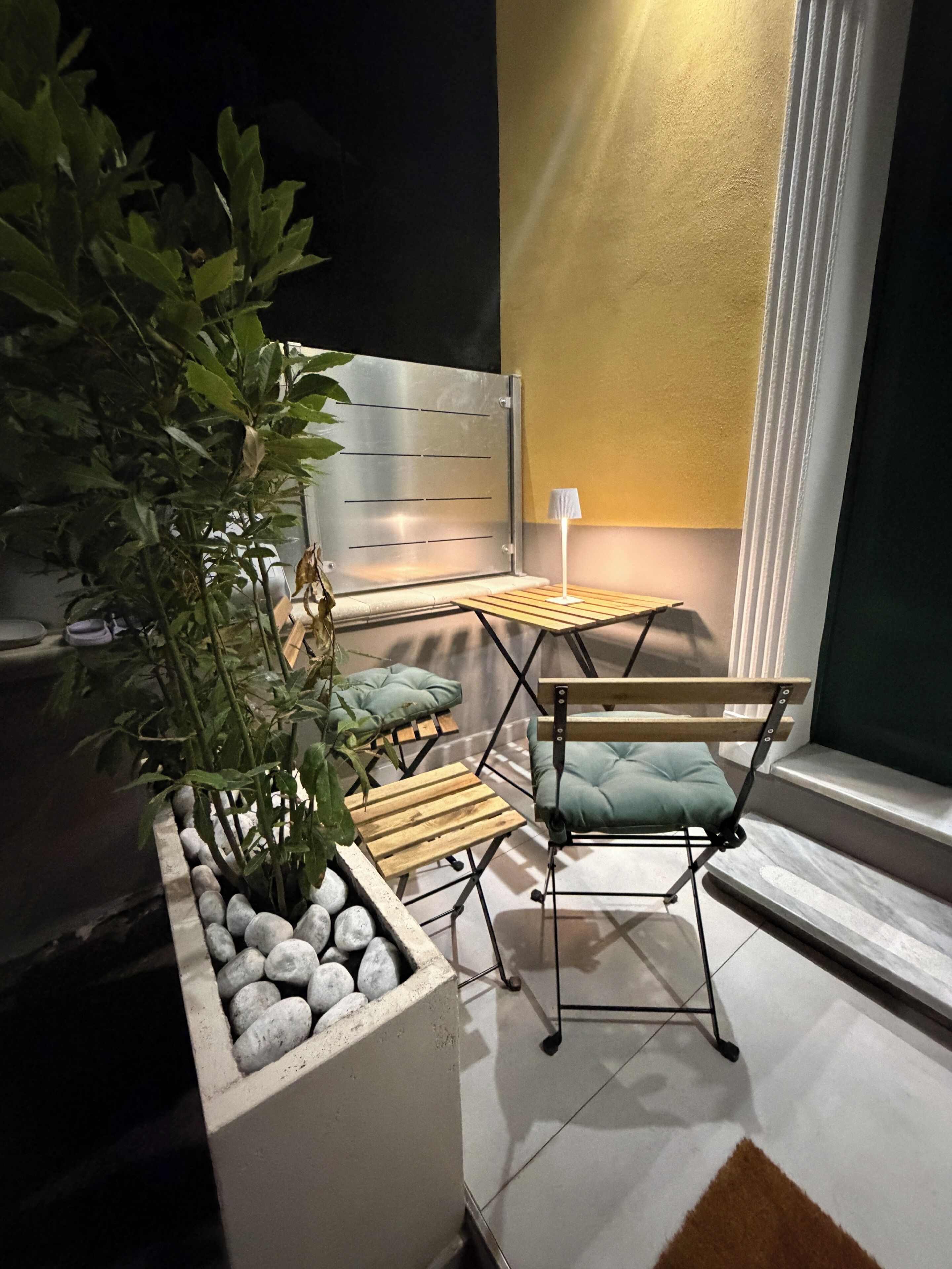 A small, cozy seating area with a table and chairs, a potted plant, and a lamp.