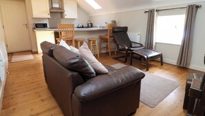 A compact living space with a sofa, a dining area, and a kitchenette. - Pen Y Grisiau (Mold)