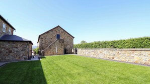 A stone building with a grassy courtyard, a stone wall, and a clear sky. - Pen Y Grisiau (Mold)