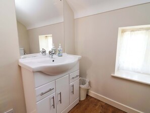 A bathroom with a white sink, mirror, and wooden flooring. - Pen Y Grisiau (Mold)