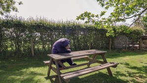 A picnic table in a grassy area with a hedge in the background. - Pen Y Grisiau (Mold)