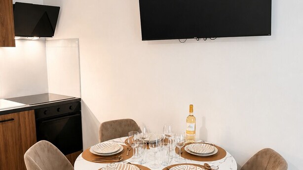 A modern dining area with a round table set for four, equipped with plates, cutlery, and glasses. - Exclusive Chic Stay! Live Next to the Eiffel Tower (Paris)