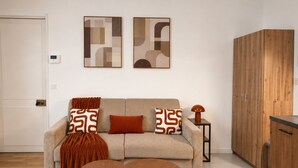 A modern living room with a sofa, two side tables, a wooden cabinet, and abstract wall art. - Exclusive Chic Stay! Live Next to the Eiffel Tower (Paris)