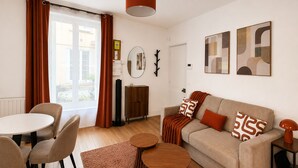 A modern living room with a sofa, two round coffee tables, a dining table with chairs, and a large window with curtains. - Exclusive Chic Stay! Live Next to the Eiffel Tower (Paris)