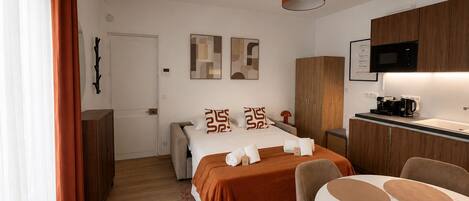 Habitación de hotel moderna con cama, escritorio, silla, microondas y cafetera.
