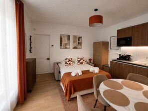 Een moderne hotelkamer met een bed, een bureau, een stoel, een magnetron en een koffiezetapparaat.
