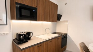 A modern kitchen with wooden cabinets, a microwave, a coffee machine, and a dishwasher. - Exclusive Chic Stay! Live Next to the Eiffel Tower (Paris)