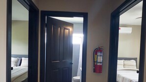 Ein Flur mit Holzboden, der zu einem Schlafzimmer mit Bett und einem Badezimmer mit Toilette führt.