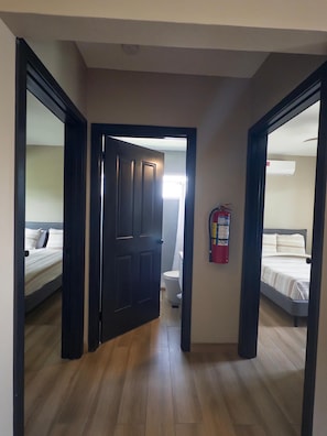 Ein Flur mit Holzboden, der zu einem Schlafzimmer mit Bett und einem Badezimmer mit Toilette führt.