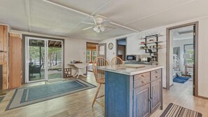 A spacious kitchen with a central island, wooden flooring, and a view of the outdoors. - Sacandaga Lake Retreat w/dock & Screened In Porch (Northville)