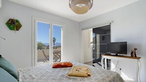 Een slaapkamer met een bed, een televisie, een bureau en uitzicht op de omgeving.