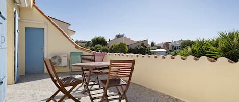 A patio with a table and chairs, a door, and a wall with a decorative edge.