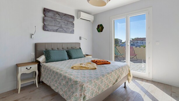 Een slaapkamer met een bed, een nachtkastje, een wandairconditioner, een wereldbol als kunstwerk en uitzicht door een glazen deur.