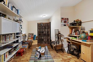 Una habitación con una amplia estantería, un escritorio con un globo terráqueo y libros, y una silla.