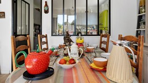 Una mesa de comedor dispuesta con diferentes platos, una tetera y un frutero.