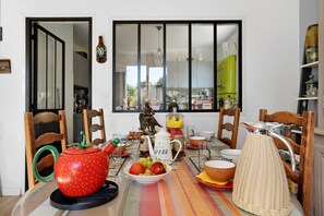 Una mesa de comedor dispuesta con diferentes platos, una tetera y un frutero.