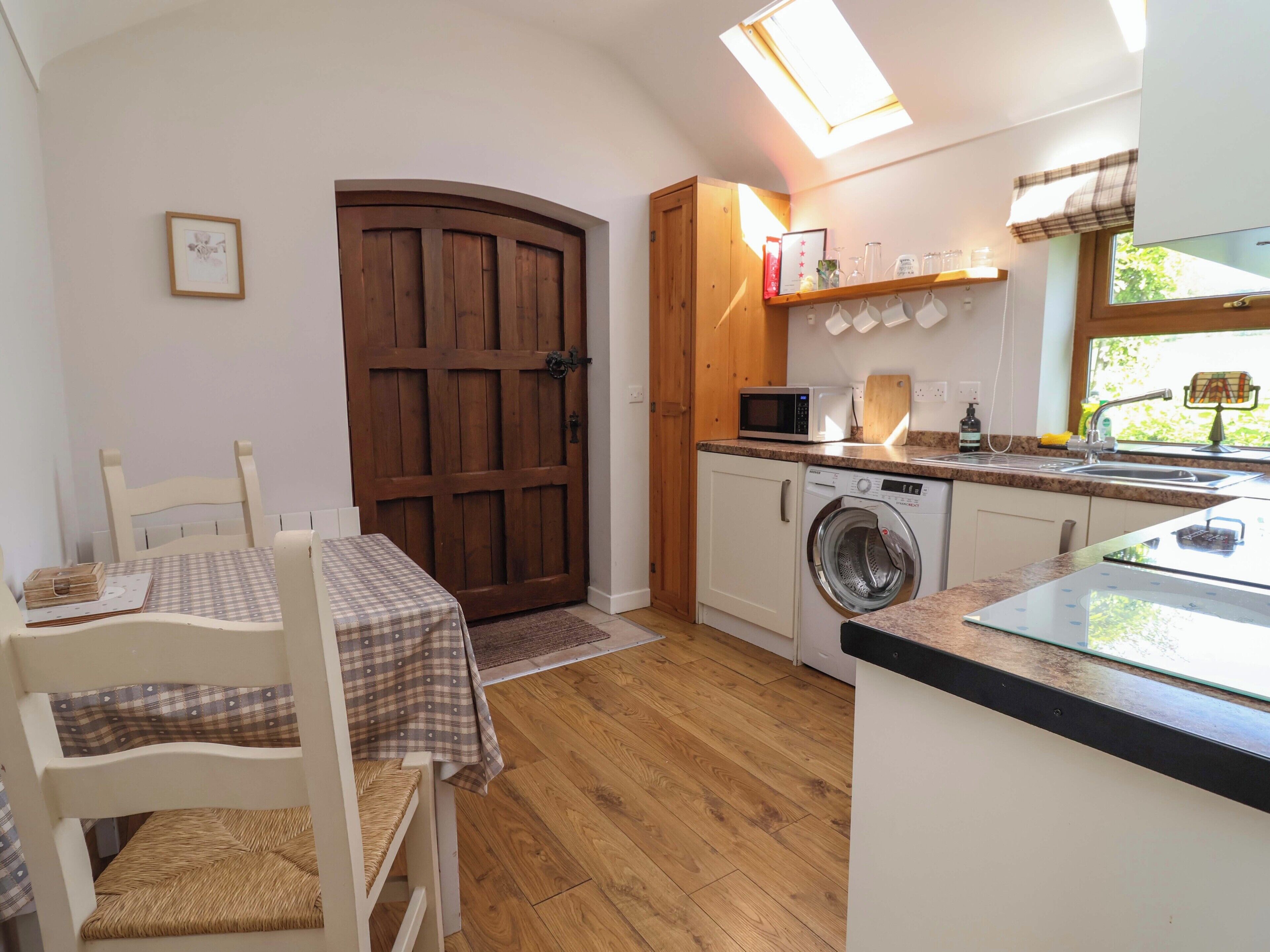 A compact kitchen with a washing machine, microwave, and a small dining area with a table and chairs.