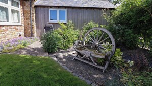 A rustic wooden shed with a window and a wheelbarrow in the garden. - Ty Haf (Mold)