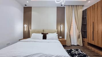 Un dormitorio moderno con una cama, mesitas de noche, lámpara de pared, ventana con cortinas y un armario de madera.