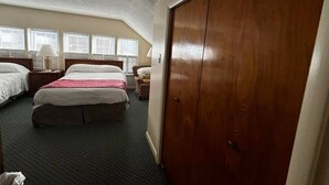 Et hotelværelse med to senge, et skab og et vindue med persienner.