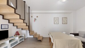 A modern living space with a staircase, a dining area, and a television. - Apartment 'La Putea Salento' with Private Terrace, Wi-Fi and Air Conditioning (Corsano)