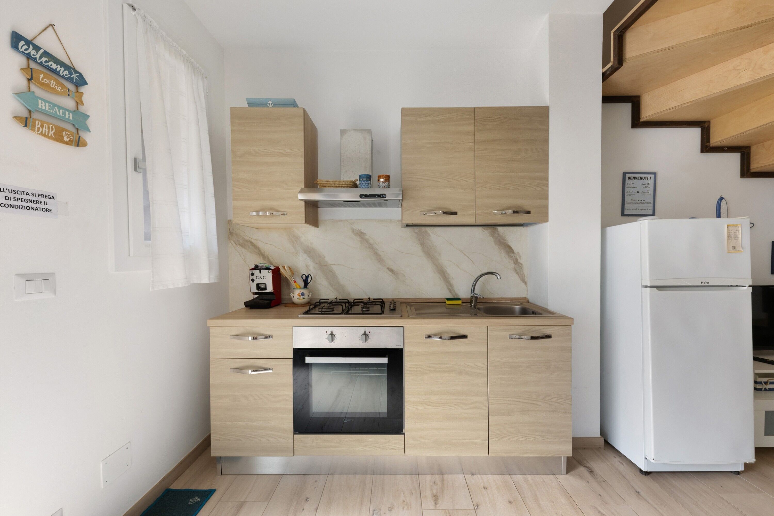 Une cuisine moderne avec des meubles en bois, un four encastré, une cuisinière à gaz et un réfrigérateur blanc.