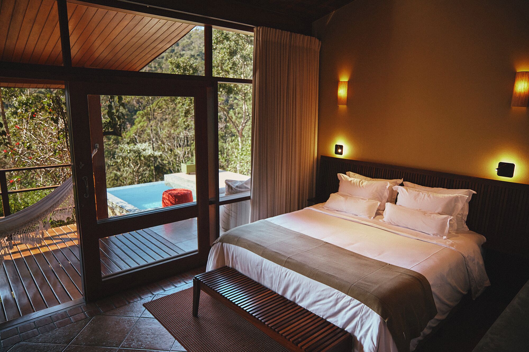 A bedroom with a large bed, a wooden headboard, and a view of a swimming pool.