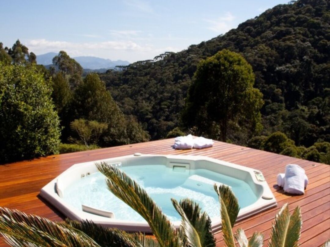 Tinaco en una terraza de madera con vista a una ladera boscosa.