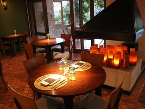 Un restaurante con mesas redondas, sillas, velas y un piano.