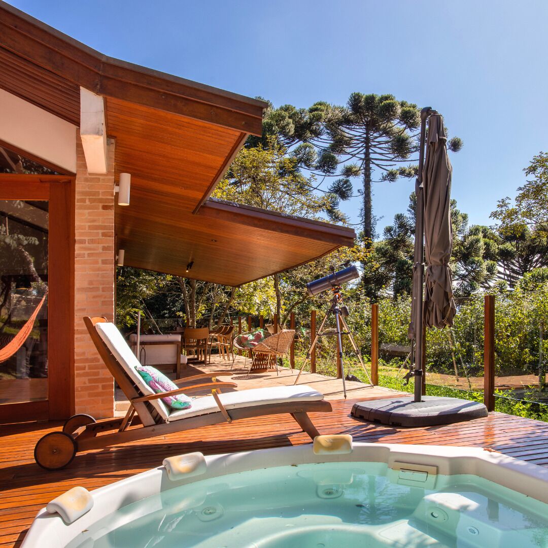 Une terrasse en bois avec des chaises longues, un jacuzzi et un télescope.