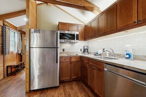 A modern kitchen with wooden cabinets, a stainless steel refrigerator, a microwave, and a sink with a faucet.