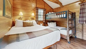 A cabin-style room with a bunk bed, two bedside lamps, and a window with curtains. - Riverfront Wilderness Cabin (Cullowhee)
